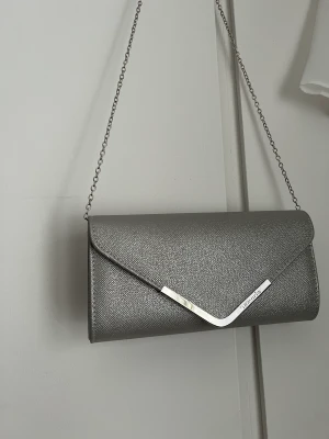 Kuvertväska - En rymlig kuvertväska med avtagbar kedja. Längd:27cm Höjd:14cm Ordinariepris 379kr