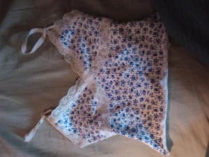 Vitt linne men blåa blommor - Den är köpt från hm för ungefär ett år sedan, när man inte använder den så korvar sig banden men sitter helt vanligt när den är på