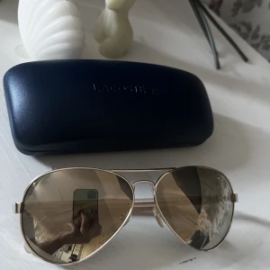 Solglasögon - Solglasögon från Lacoste, aldrig använda då jag fick dem men passade inte riktigt min stil 💓 inga repor eller något, har bara legat i fodralet. Bågarna är ljusrosa, fodralet ingår 💓