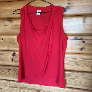 Linne - Fint rött linne som är två lager på framsidan. Det finns en liten fläck på höger  baksida axel. Knappt synbar och går säkerligen att få bort. Annars inget att anmärka på.