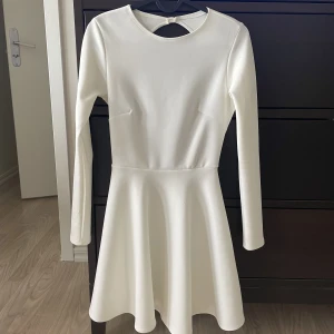 Vit klänning  - Vit klänning från Nelly som passar till student & annan fest. Tjockt & ordentligt tyg med öppen rygg. Liten fläck på armen som garanterat lär gå bort i tvätten. Använd endast 2 gånger.  Köpare står för frakt