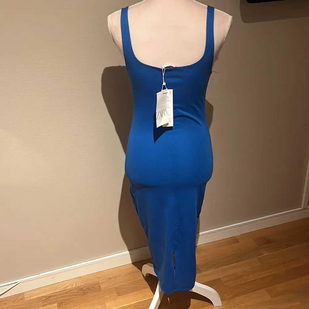 En helt oanvänd blå klänning med prislapp kvar! Har en slits där bak på klänningen! Frakten kostar 65kr!!!. Klänningar.