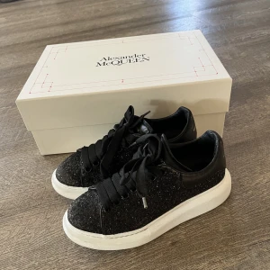 Alexander McQueens - Väldigt varsamt använda. Kartong, extra snören och äkthetsbevis finns. Svartglittriga.