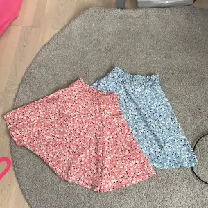 Ett pack med en rosa blommig kjol och en blå blommig kjol.58cm i midjan på båda kjolarna 