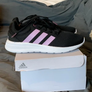 Svarta skor ifrån adidas  - Svarta skor med rosa detaljer och vit sula ifrån Adidas, helt oanvända i storlek 39 1/2! 