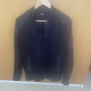 Hugo Boss cardigan/jacka - Hej, säljer detta fina plagg. Utmärkt skick. Köpt för 3799kr men säljer nu för 600kr!!! (kan diskuteras). Storleken fungerar för S/M. En överlag jättefin och skönt plagg. Grymt pris för denna fina plagg med extremt bra skick