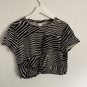 Croppad t-shirt  - Säljer en svart/beige mönstrad croppad t-shirt. Knappt använd. Skriv för mer bilder🤎