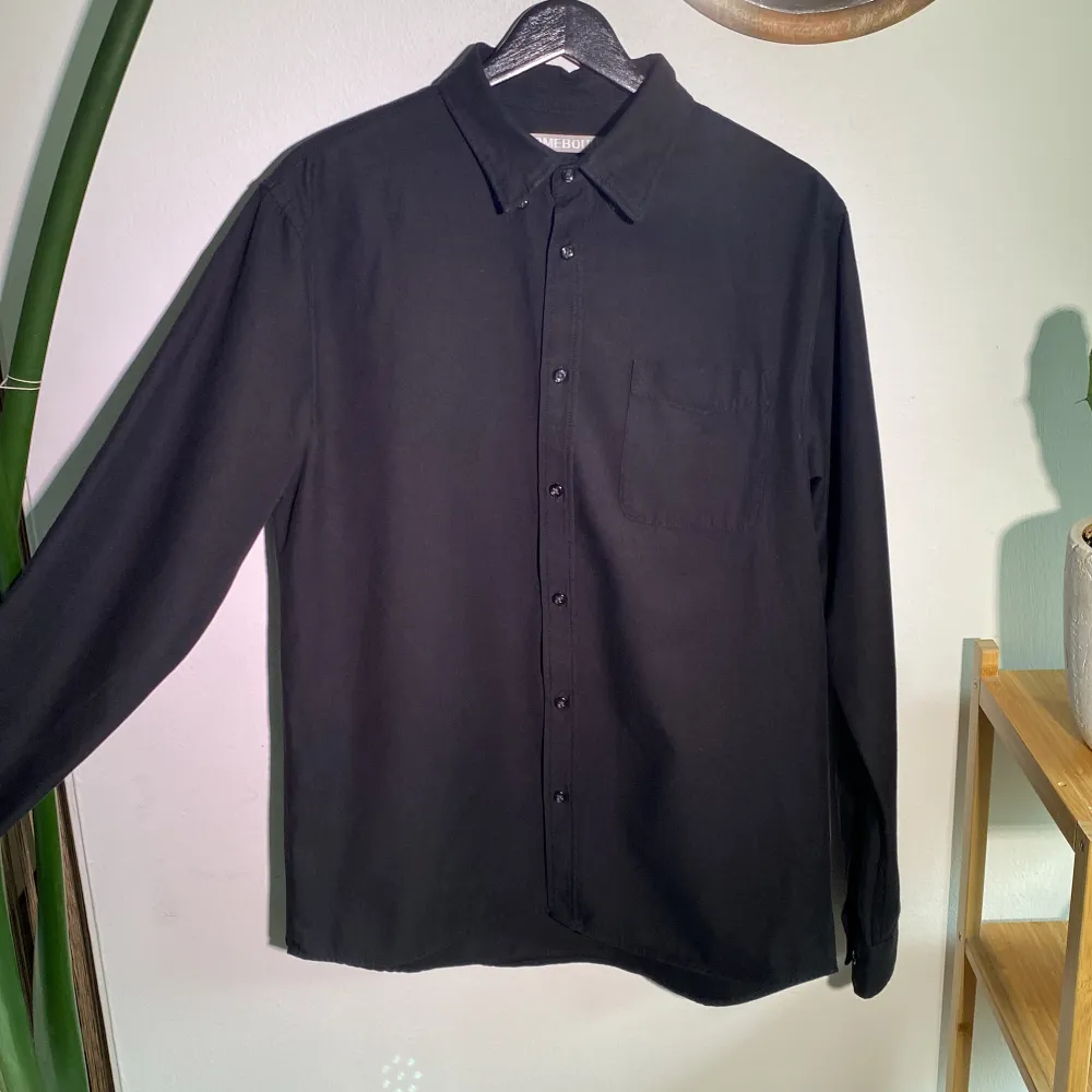 En HOMEBOUND Skjorta i kraftigt bomull med framficka.  (Mörkare än den framstår på bilden) Regular medium, sann i storleken. Längd 75cm. Skjortor.