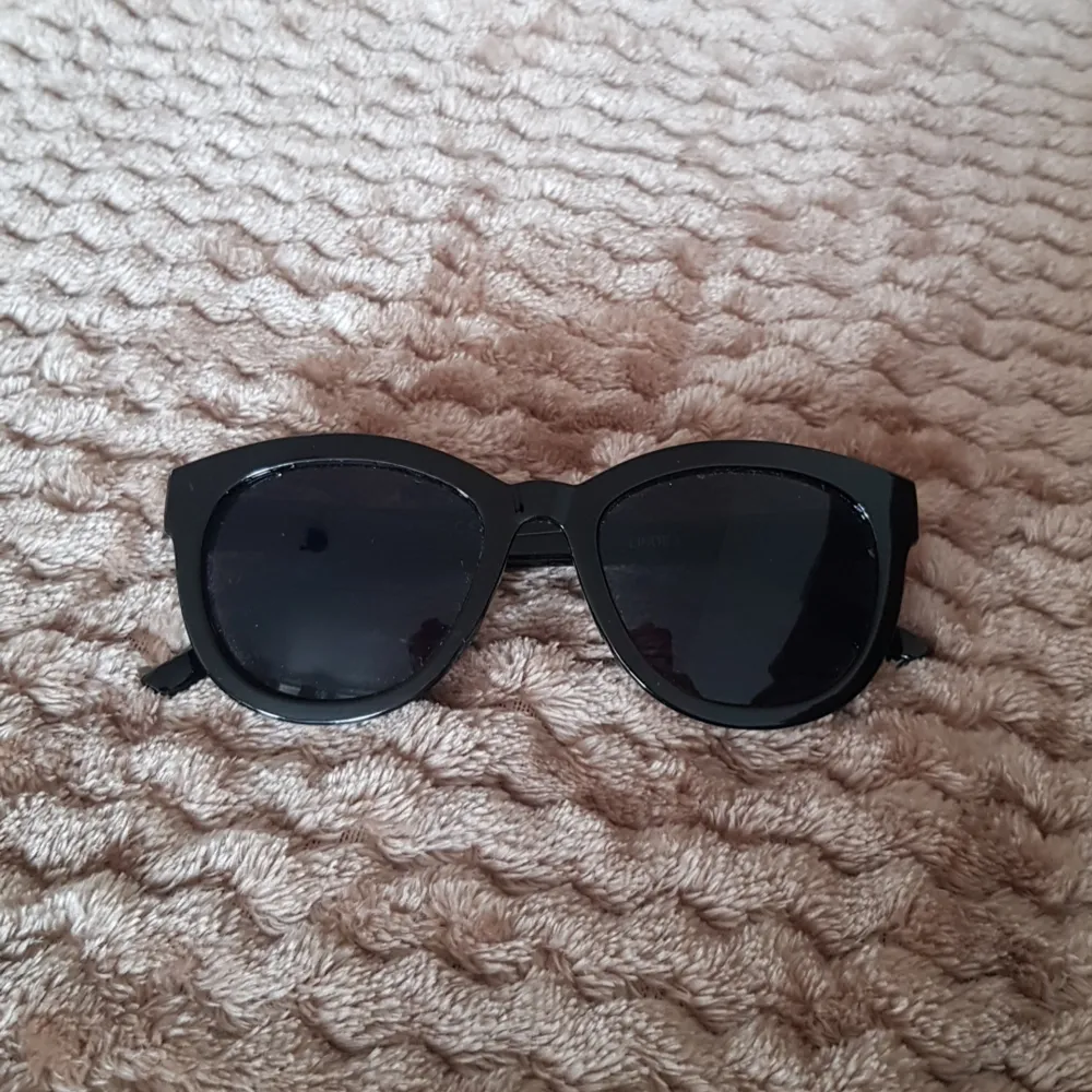 Svarta blanka solglasögon med svart glas. Accessoarer.