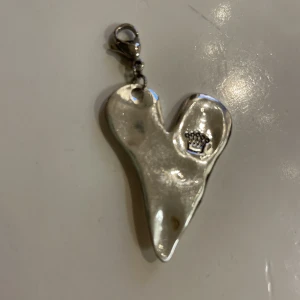 Berlock  - Hamrat hjärta ifrån diddi att hänga kring halsen i en silverkedja. Hjärtat är för stort att ha som berlock i ett armband. 