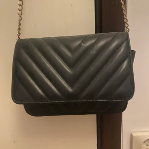 Väska från H&M - Jättefin svart väska från H&M med guldig kjedja.❤️