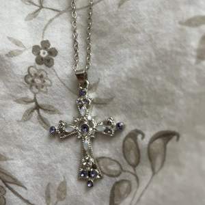 Så fint kors halsband med vita o lila stenar! 