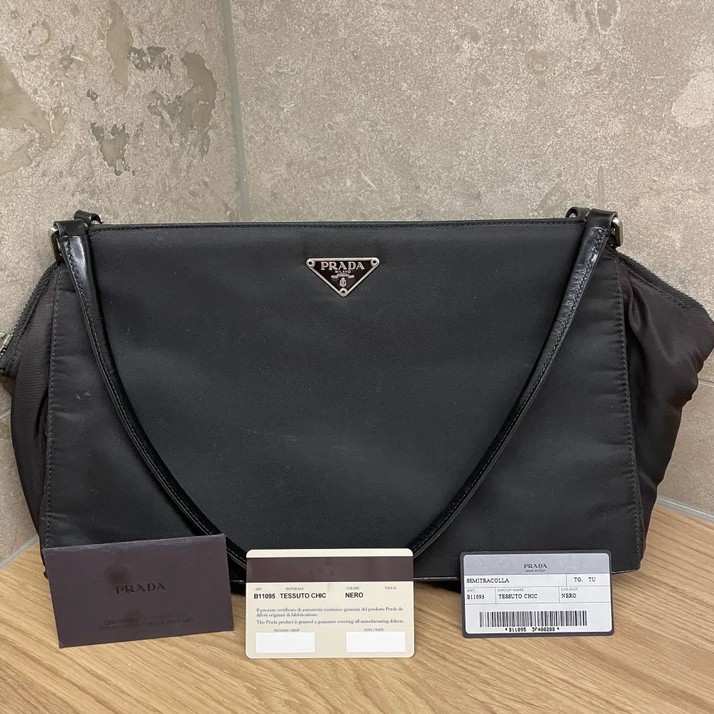 Prada handväska  Nylon Modellnummer: B11095 Färg: Svart Material: Nylon/läder Mått:  W32 × H18.5 × D7cm  Väldigt fräsch. Certifikat ingår. Billigare vid snabb och smidig affär. Finns på Östermalm i Stockholm. Kan givetvis skickas.. Väskor.