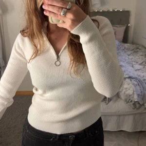 Tröja - Supersnygg vit/crémevit ribbad zipup-tröja från na-kd🤍💫 Justerbar dragkedja.  Säljer då den tyvärr aldrig blivit använd Storlek S