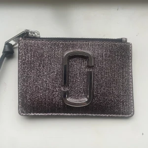 Marc jacobs plånbok - Säljer denna så så fina plånboken ifrån marc jacobs, nypris runt 1200 men säljer för 800💓säljer pågrund av att den inte kommer till användning längre, färgen är lite oklart, blandning mellan silver och lite lila aktig älskar!! 