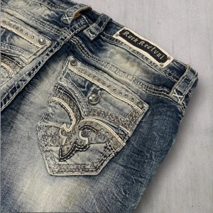 R16 Rock Revival Bootcut jeans  - Rock Revival jeans i model Boot 💜 Tag 30W 💜Midja (rakt över) 42cm 💜 Innerben 73cm 💜 Ytterben 99cm 💜 Benöppning 21cm 💜 Fläckar, uppsydda 💜Våra mått blir W=33, L=28 💜 Men jämför alltid måtten💜R16