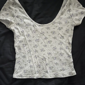 vit blommig topp  - jättegullig urringad vit topp med lila blommor på🌸 ifrån h&m och knappt använd. storlek XS men passar även S då den är stretchiga. samma urringning på baksidan 💓 inga defekter!