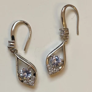 Örhängen  - Små silverfärgade örhängen med rhinestones  Okänt material 