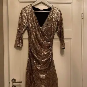 Så snygg klänning till alla festligheter! Omlottmodell så den sitter väldigt fint på. Guld/brons färgad. Det saknas några paljetter på baksidan men skulle inte säga att man lägger märke till det när den sitter på.