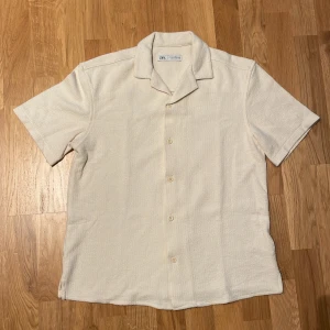 ZARA skjorta med textur - Gräddvit skjorta. Storlek S. Relaxed fit. Bowlingkrage. Kortärmad. Bra skick. Använd endast en gång. Nypris 429kr