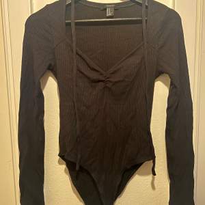 Long sleeved body suit with snaps and a tying detail at the neck  