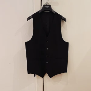 Kostymväst Tiger - Kostymväst från Tiger of Sweden. Passar perfekt till dig som vill sätta det lilla extra fina till din svarta kostym. Använd men så gott som ny / oanvänt skick. Svart storlek 48. Säljs för 800 kr ( nyköp 1699 kr)