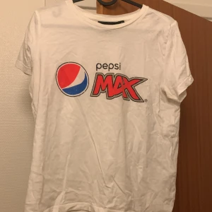 Pepsi t-shirt - En vit t-shirt med trycket pepsi. Ett litet hål på ryggen som knappt syns (se bild tre). 