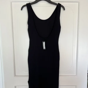 Svart ribbad klänning med slits  - Svart ribbad klänning med slits perfekt för sommaren! Öppen i ryggen enligt bild. Aldrig använd, lappen sitter kvar. Från Boohoo
