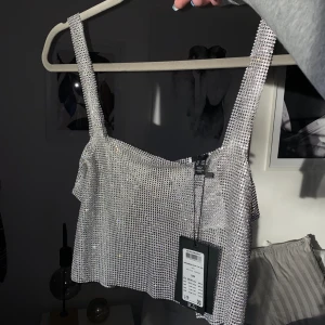 Silvrig topp - Oanvänd ”strass”topp med prislapp kvar. Köpt i november 2021 men har aldrig haft användning av den. Nypris 400kr.💙