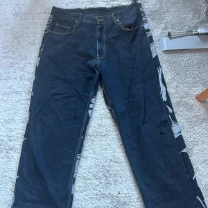Ascoola jeans  - Ascoola jeans men snyggt motiv på baksidan. Finns ett hål på knät och ett av skärpfästena har lossnat, annars i fint skick!! (Storlek 38 man) 