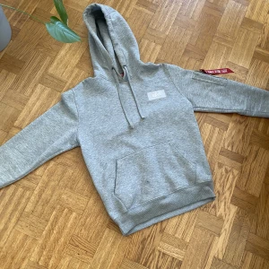 Alpha Industries Hoodie  - Alpha Industries Hoodie - S  Använd en del men fortfarande i mycket bra skick, inga stretch märken på trycket i ryggen.