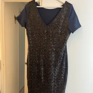 En fin mörkblå klänning med paljetter på framsidan av klänningen, från salt. 