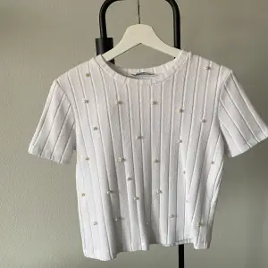 Lyxig t-shirt med vita pärlor. Är i fint skick. skickar gärna fler bilder om du är intresserad. Ps frakt tillkommer 💫