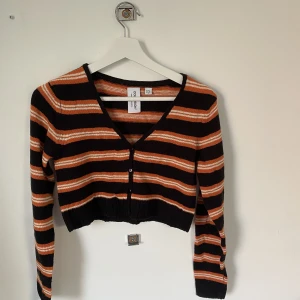 Randig kofta/topp - Croppad randig kofta/topp i svart, orange och vit! Köpt på asos