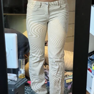 Lågmidjade jeans - Ett par lågmidjade jeans med som vågiga ränder över hela byxorna. Dem är även utsvängda vid vader och fötter, Aldrig använda då jag växte ur dem snabbt 