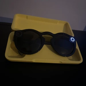 Snapchat Solglasögon - Säljer ett par solglasögon från Snapchat!   Du kan använda dem när som helst, t.ex. om du går på fest eller när du ska göra något annat kul. Genom att trycka på den lilla knappen på sidan av glasögonen så spelar de in allt i tio sekunder. Även bilder