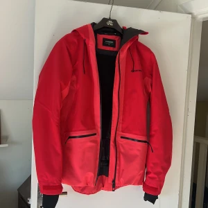 Skidjacka  - Rosa/röd skidjacka i stl 36, men funkar absolut för en mindre 38 oxå. Använd en säsong men är i nyskick. Luvan är stor och går över skidhjälmen. Håller värmen. Köpt på Stadium, nypris 1799kr