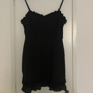Klänning från NA-KD - Svart kort volangklänning. Säljer på grund av för liten. Använd ca 2-3 gånger. Köpt för 399 kr. Frakt tillkommer!