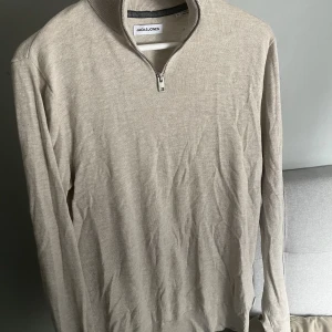 Half zip tröja - Tunnstickad halv zip tröja från Jack & Jones i beige färg, storlek S. Knappast använd så väldigt bra skick! Säljer pga för liten. Nypris 400! Hör av er vid frågor eller intresse!