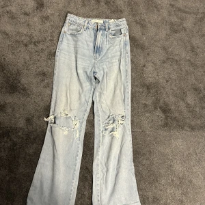 Högmidjade jeans - Högmidjade jeans med hål från stradivarius storlek 34. Jeansen är uppsydda för längd 165cm men går att sprätta upp. 