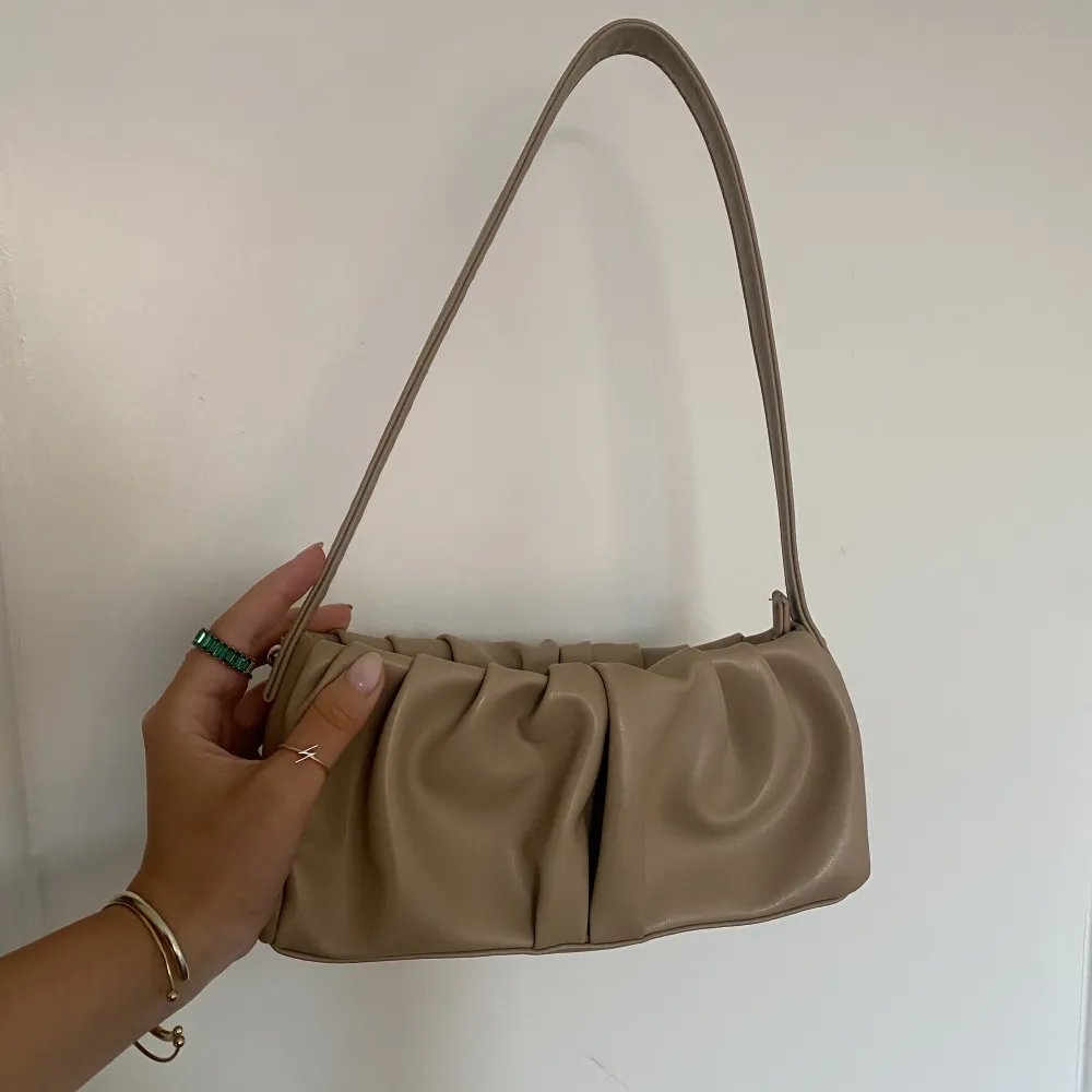 Sjukt snygg beige veckad handväska från Asos som endast är använd 1 gång, som helt ny. Ca 25cm lång & 9cm bred. Perfekt till dag & fest<3. Väskor.