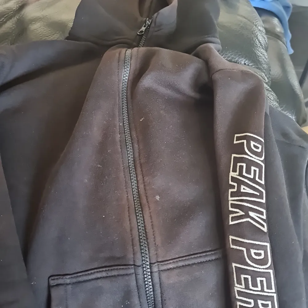 En svart peak performance kofa inte så bra skick och ganska smutsig men det går bort i tvätten nog. Hoodies.