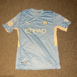 Man city tröja  - Säljer denna använda man city tröja som användes säsongen 21/22 och på ryggen är det de bruyne 17. Tröjan är i okej skick då namnet är lite sliten annars är den i i gott skick. Den är äkta. 