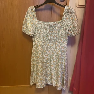 Blommig klänning - Kort blommig klänning, sliten vid dragkedjan men annars fint skick!! Fick dne från min syster men har bara använt 1 gång själv!! Skriv för mer info eller bilder, priset går alltid att diskutera ;D