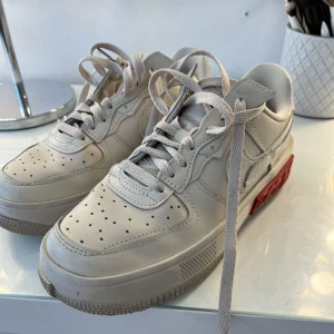 Nike air force - Beigea Nike air force skor med röda detaljer! Använda 3 gånger så dem är i väldigt fin skick, säljer dem nu pga kommer aldrig till andvändning, storlek 38!!