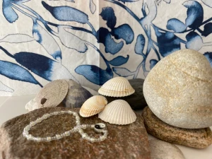 Armband med berlock - Armbandet är gjord med kärlek och tålamod. Armbandet är gjord på ett elastiskt tråd med vit och ljusblåa pärlor. I mitten av armbandet är det en berlock. Armbandet är väldigt tåligt och är bad och dusch säkert.