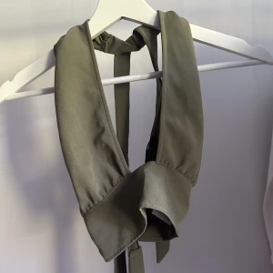Halterneck crop top - khakigrön halterneck top med knytning både runt halsen samt kroppen, därmed justerbar.
