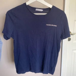 Calvin Klein t-shirt  - En mörkblå Calvin Klein t-shirt i storlek 152 men sitter som en XS på mig. Ganska använd och är i hyfsat skick, det ända som är lite slitet är trycket på vänster sida.💕