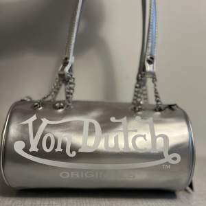 Silver Mini Bag från Von Dutch Originals. Vegansk.  Väskan är helt oanvänd och fint skick. Loggor på båda sidor. Så snygg! 