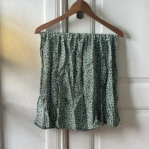 Grön kjol med blommor. Midi i längden och två slitsar vid varje ben.